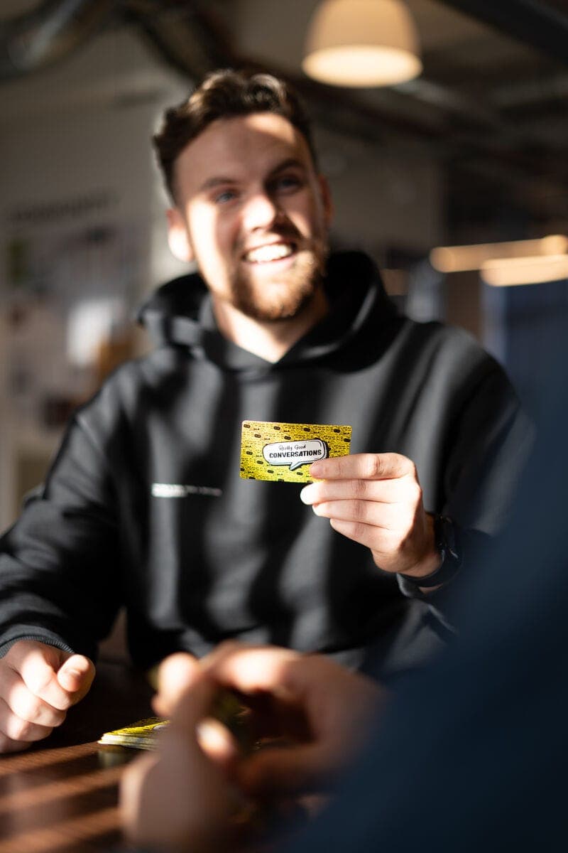 Man smiling while holding a Really Good Conversations card